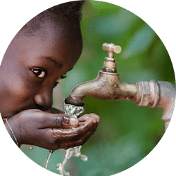 A child drinking water from a hand pump in Africa